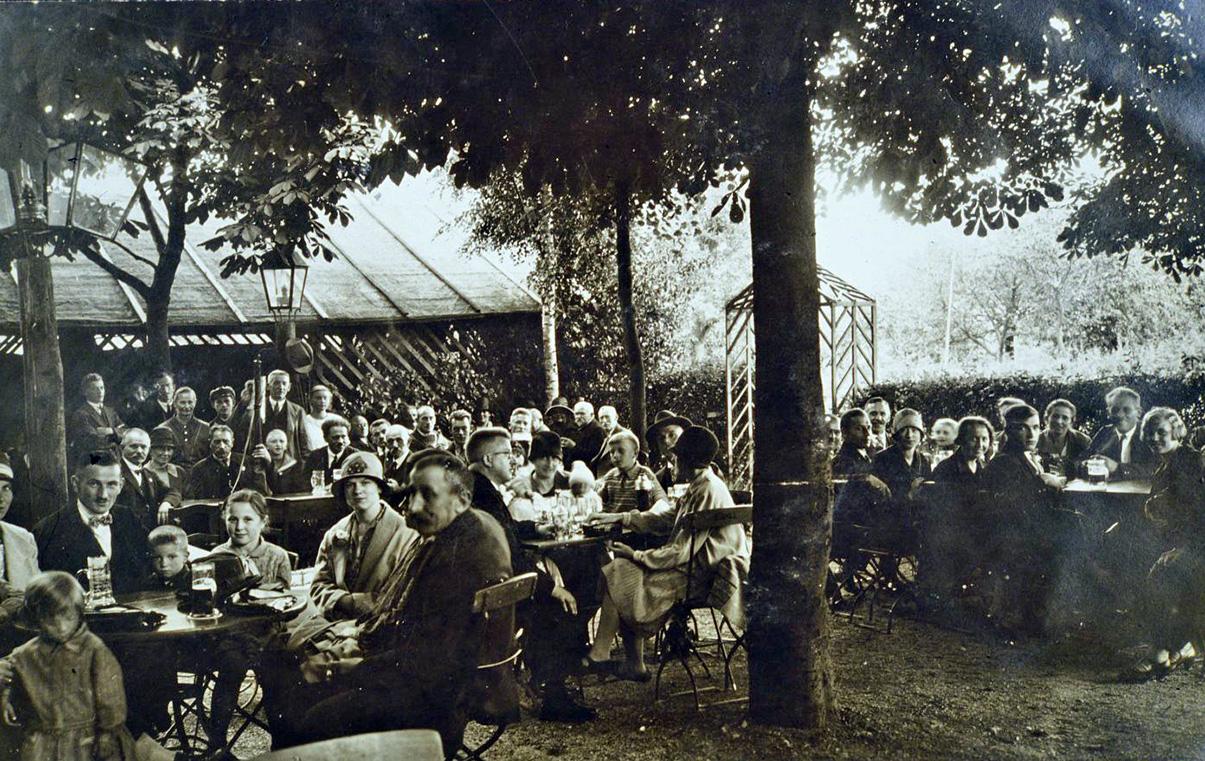 Um welchen Biergarten handelt es sich hier? Es ist ein Thema, das die Treuchtlinger richtig beschäftigte. Selten zuvor gab es so viele Anrufe in der Redaktion, Hinweise und auch regen Austausch im Internet. Nachdem wir meldeten, dass der Biergarten anhand von Zeitzeugenaussagen als der am Gasthaus "Zur Brücke" identifiziert sei, gibt es nun einen Fotohinweis, dass es sich um den Biergarten am Weinbergshof handeln müsse. Dieses Bild ist eine Postkarte. Sie ist auch in dem Band „Treuchtlingen in alten Ansichten“ zu sehen, der einst von Fritz Korn herausgegeben wurde. Die zahlreichen Biergärten damals waren sich offenbar sehr ähnlich, sowohl in Größe, als auch in der Art ihrer Ausstattung. Fast alle hatten eine Art Pavillon, um darunter bei Regen zu sitzen. Man nannte diese Art Schuppen auch „Neugier“, weil man von innen nach außen blicken konnte, aber nicht umgekehrt. Unser Foto zeigt höchstwahrscheinlich den Weinbergshof-Biergarten aus nördlicher Richtung, vom Steingebäude aus aufgenommen. Im Hintergrund sind darauf etwas tiefer Obstbäume zu sehen, die auf dem anderen Bild vom Weinbergshof im linken Bereich abgebildet sind. Als Personen auf dem Bild bestätigt sind der Friseurmeister Krejci sowie am rechten Tisch hinten Michael Möhrlein (geboren 1871, gestorben 1942), dessen Tochter Betty (geboren 1918) und Frieda Winter (geboren 1908). Aus dem Alter der Personen ergibt sich als ungefähres Aufnahmedatum das Jahr 1935.