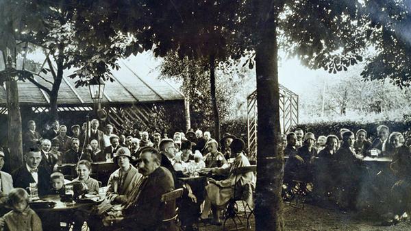 Um welchen Biergarten handelt es sich hier? Es ist ein Thema, das die Treuchtlinger richtig beschäftigte. Selten zuvor gab es so viele Anrufe in der Redaktion, Hinweise und auch regen Austausch im Internet. Nachdem wir meldeten, dass der Biergarten anhand von Zeitzeugenaussagen als der am Gasthaus "Zur Brücke" identifiziert sei, gibt es nun einen Fotohinweis, dass es sich um den Biergarten am Weinbergshof handeln müsse. Dieses Bild ist eine Postkarte. Sie ist auch in dem Band „Treuchtlingen in alten Ansichten“ zu sehen, der einst von Fritz Korn herausgegeben wurde. Die zahlreichen Biergärten damals waren sich offenbar sehr ähnlich, sowohl in Größe, als auch in der Art ihrer Ausstattung. Fast alle hatten eine Art Pavillon, um darunter bei Regen zu sitzen. Man nannte diese Art Schuppen auch „Neugier“, weil man von innen nach außen blicken konnte, aber nicht umgekehrt. Unser Foto zeigt höchstwahrscheinlich den Weinbergshof-Biergarten aus nördlicher Richtung, vom Steingebäude aus aufgenommen. Im Hintergrund sind darauf etwas tiefer Obstbäume zu sehen, die auf dem anderen Bild vom Weinbergshof im linken Bereich abgebildet sind. Als Personen auf dem Bild bestätigt sind der Friseurmeister Krejci sowie am rechten Tisch hinten Michael Möhrlein (geboren 1871, gestorben 1942), dessen Tochter Betty (geboren 1918) und Frieda Winter (geboren 1908). Aus dem Alter der Personen ergibt sich als ungefähres Aufnahmedatum das Jahr 1935.
