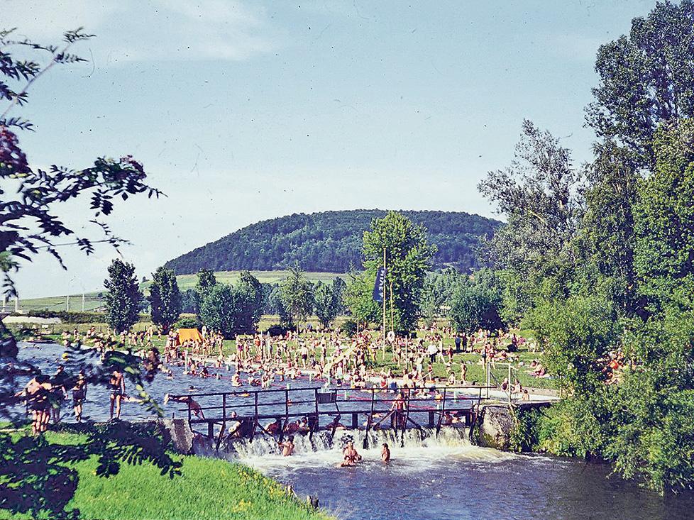 Dieses Bild zeigt das ehemalige Altmühlbad Anfang der 1970er Jahre. Im „kollektiven Gedächtnis“ hat sich unter anderem die Geschichte von der „toten Sau“ erhalten, die in den 1960er Jahren einmal die Altmühl hinuntergetrieben und im Freiband gelandet sein muss. Das hat die Leute damals aber nicht vom Baden abgehalten. Es war eher ein Objekt allgemeiner Belustigung. Der Eintritt kostete in den 1960er Jahren 20 Pfennig, die Zehnerkarte eine Mark. Aber bei Weitem nicht alle zahlten, denn von der Elkan-Naumburg-Straße aus konnte man oberhalb in den Fluss springen und ins Bad hineinschwimmen. Später verhinderte dies ein Stacheldrahtverhau auf Höhe der heutigen Promenadenbrücke. 1974 wurde das Bad vom Gesundheitsamt geschlossen. Kurz darauf entstanden das Wellenbad und später die Altmühltherme mit dem heutigen Freibad. Zur kompletten Geschichte des Flussbads geht es hier.