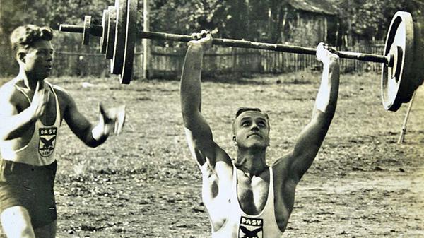 Auf die Frage nach den Namen der zwei Gewichtheber, die auf diesem Foto auf dem Platz vor der damaligen Turnhalle zu sehen sind, sowie nach der Geschichte des Vereins DASV 1894 antwortete unsere Leserin Helga Pfahler. Der Mann mit den Gewichten ist Hermann Neumeyer, der Bruder des ehemaligen Bergsteigers. Er war Bäcker bei der Konditorei Stegmeier in der Bahnhofstraße. Das Bild muss vor 1936 aufgenommen worden sein, denn der DASV (Deutscher Athletik Sportverband), dessen Vereinswappen klar zu erkennen ist, wurde im Rahmen der Gleichschaltung durch die Nazionalsozialisten verboten. Der DASV stammte aus der Arbeiterbewegung. Neumeyer arbeitete später bei Krauss-Maffei. Der Ahtlet links ist Ernst Drießlein, Jahgang 1904. Dies wurde uns von dessen Sohn Ernst mitgeteilt. Aus dem Besitz der Familie Drießlein stammt auch das Foto.