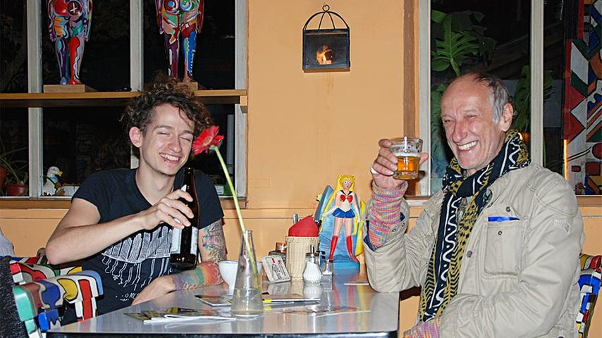 Marius (22) macht in der Kofferfabrik derzeit eine Ausbildung zum Restaurantfachmann und hat daher, wenn er bedient, viel mit den Gästen zu tun. In der entspannten Atmosphäre der Kulturmanufaktur mit Restaurant, Bar und Konzertraum fühlt er sich wohl. Peter (59) gehört hier zum Inventar. Er hat schon um die Ecke gewohnt als "die Koffer" vor 20 Jahren eröffnet hat. Regelmäßig ist er allerdings erst seit sieben Jahren zu Gast, als der jetzige Besitzer Udo Martin den Laden übernommen hat. Seitdem hat er das Ambiente auch selbst mitgestaltet. Beispielsweise bemalte er Stühle und Tische. "Im Sommer ist das hier mein Garten. Im Winter komme ich her, weil es bei mir zuhause zu kalt ist", sagt Peter lachend. Vor allem gefällt ihm an der Kofferfabrik aber, dass er regelmäßig neue, interessante Leute kennenlernt: "Und das macht für mich eine Kneipe aus".