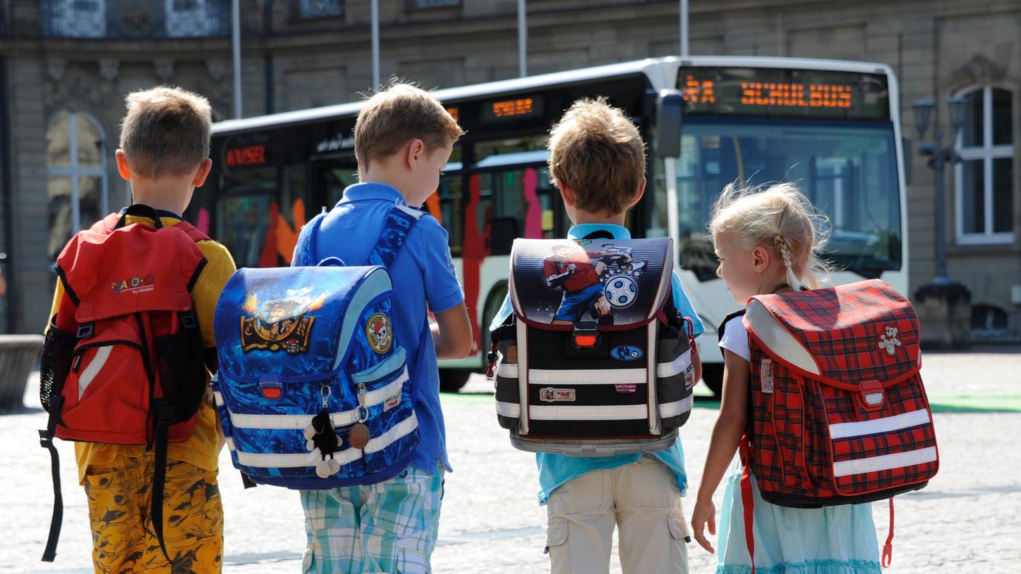 Schulkinder stehen vor einem Bus: Es handelt sich um ein Symbolbild.