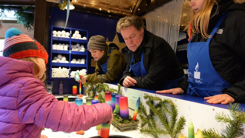 Am Haus der Wichtel auf der Erlanger Waldweihnacht können die Kinder selbst  Kerzen herstellen. Ernst Stäblein (2.v.l.) und Sohn David helfen dabei..Foto:  Klaus-Dieter Schreiter