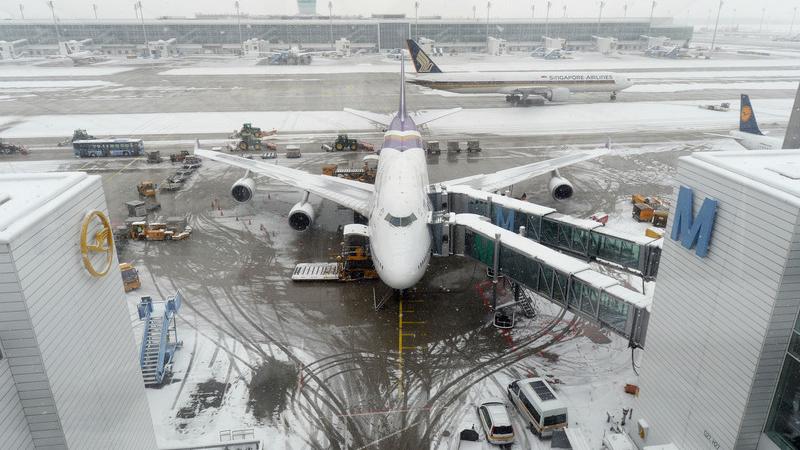 Ein Flugzeug wartet auf dem schneebedeckten Flughafen in München.