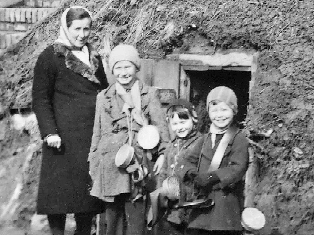 Für den Fotografen posieren eine Frau und drei Kinder vor dem Unterstand in der Puschendorfer Straße, die Gasmasken waren immer dabei.