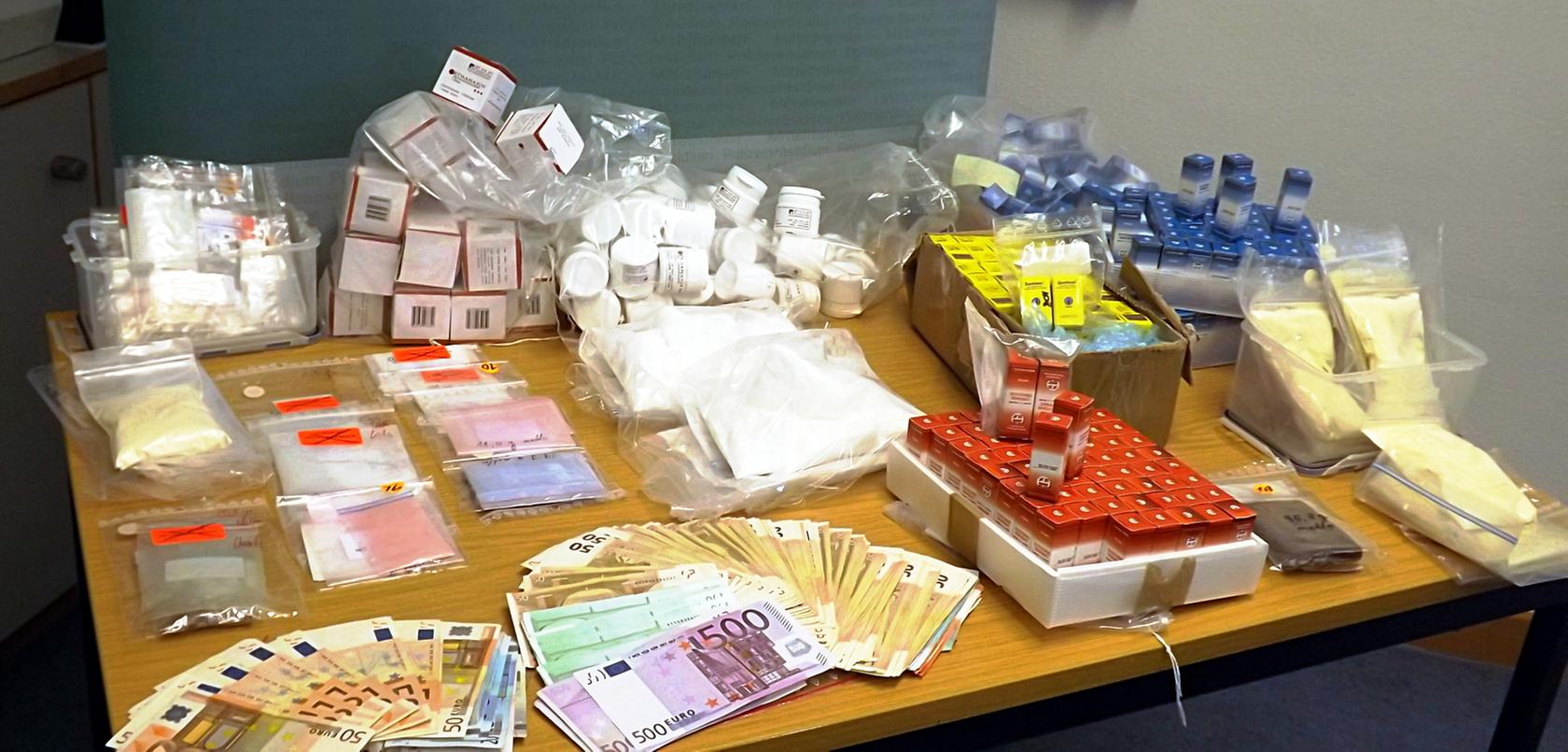 Die Polizei präsentierte einen Teil der beschlagnahmten Ware. Hier: verschiedene beschlagnahmte Drogen-Packungen, Päckchen und Geldscheine auf einem Tisch