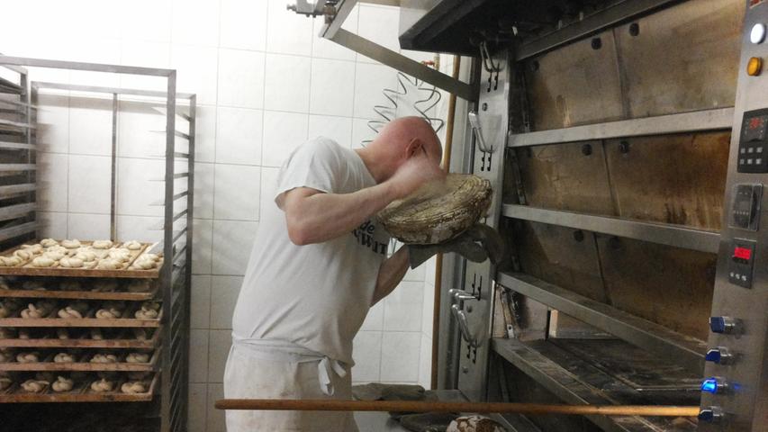 Johannes Schwarz klopft auf ein frisch gebackenes Brot. Anhand des Geräuschs erkennt er, ob es schon fertig ist.