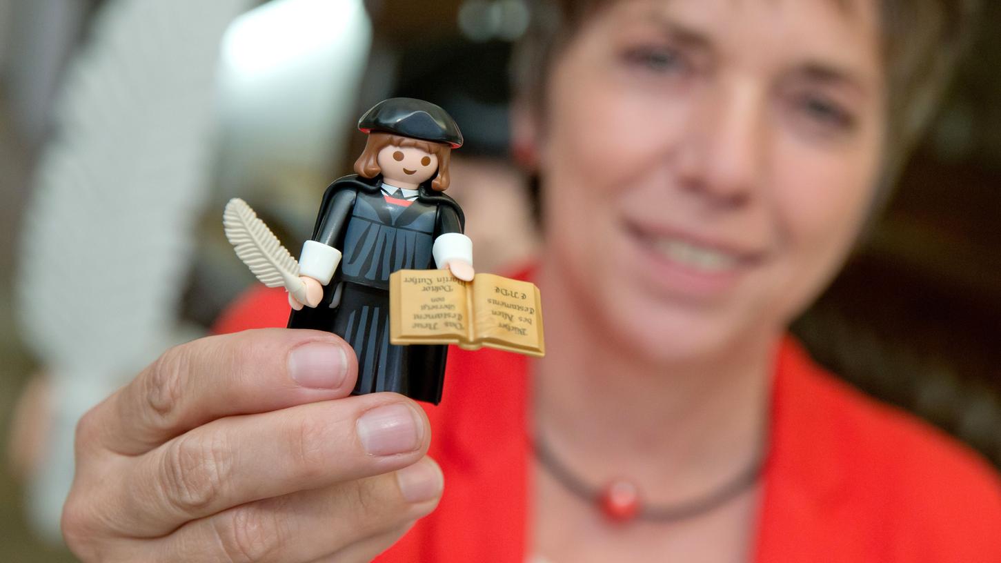 Die frühere Ratsvorsitzende der Evangelischen Kirche in Deutschland (EKD), Margot Käßmann, hält am Donnerstag im Fembohaus in Nürnberg Martin Luther als Playmobil-Figur in der Hand.