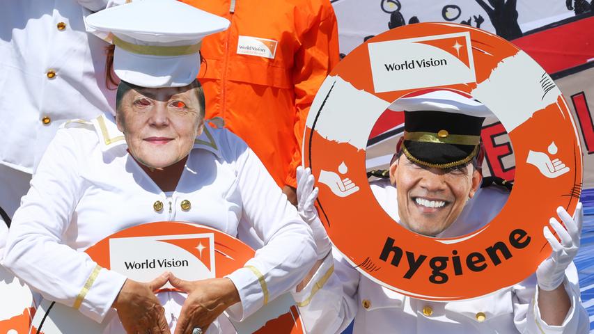 Mitglieder von "World Vision" nehmen den US-Präsidenten Barack Obama und Bundeskanzlerin Angela Merkel aufs Korn.