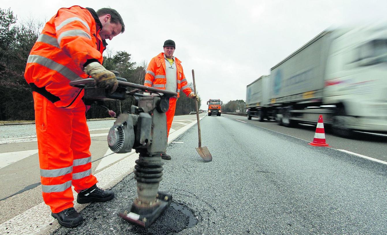 Die Schlaglöcher müssen bei laufendem Verkehr repariert werden. Die Schlaglöcher müssen bei laufendem Verkehr repariert werden.