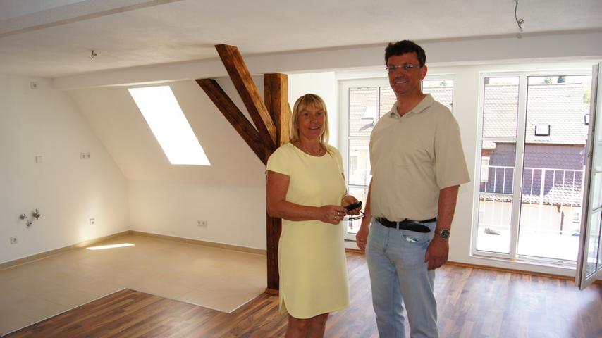 Viola Korneli und Alexander Dworschak in einem Wohnzimmer, links der Platz für die Küchenzeile, rechts der Balkonzugang.