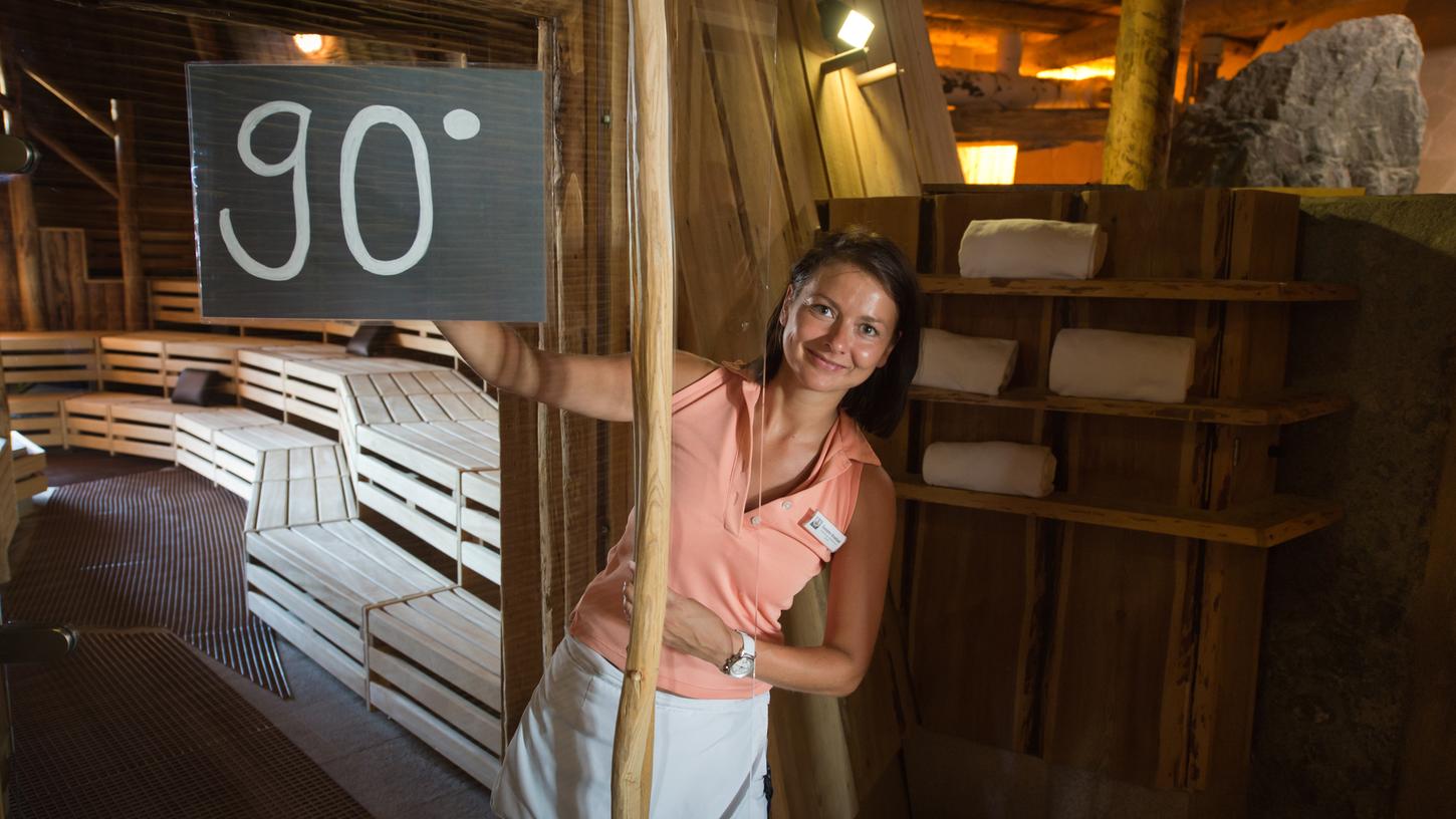 Die Mitarbeiterin der Therme Erding in Erding bei München (Bayern), Susann Knebel, hält am 01.07.2015 ein Schild mit der Aufschrift "90 Grad" an die Tür einer Sauna in der Therme Erding.