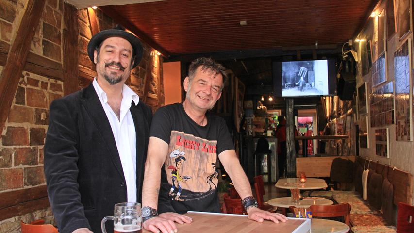 Seit zehn Jahren ist der gebürtige New Yorker Andrew (links) in Erlangen - und er ist dem ersten Café, das er hier besucht hat, treu geblieben: dem Café Beisl . Dreimal pro Woche genießt er einen Kaffee oder ein Bier nach der Arbeit, im Sommer besucht er das Café Beisl sogar noch öfters. "Krug Bräu" mag er besonders, doch er probiert auch gerne andere Sorten. Und was ist das Besondere an diesem Café für ihn? Die familiäre Atmosphäre und die "beste Musik" mit Blues, Jazz, Country. Außerdem lerne er hier interessante Menschen kennen, zum Beispiel den Wirt Nico. Nico hat das Café vom Tresen aus kennengelernt: Anfangs war er selber Gast hier, und nachdem er sich hier so richtig wohl fühlte, hat er es einfach übernommen. Seine (Stamm-)Gäste sind unterschiedlicher Couleur vom Studenten bis zum Rentner. Man kennt sich, Jung und Alt sitzen oft zusammen und trinken eines der vielen fränkischen Biere, das Beisl anbietet. Seit zehn Jahren ist der gebürtige New Yorker Andrew (links) in Erlangen - und er ist dem ersten Café, das er hier besucht hat, treu geblieben: dem Café Beisl . Dreimal pro Woche genießt er einen Kaffee oder ein Bier nach der Arbeit, im Sommer besucht er das Café Beisl sogar noch öfters. "Krug Bräu" mag er besonders, doch er probiert auch gerne andere Sorten. Und was ist das Besondere an diesem Café für ihn? Die familiäre Atmosphäre und die "beste Musik" mit Blues, Jazz, Country. Außerdem lerne er hier interessante Menschen kennen, zum Beispiel den Wirt Nico. Nico hat das Café vom Tresen aus kennengelernt: Anfangs war er selber Gast hier, und nachdem er sich hier so richtig wohl fühlte, hat er es einfach übernommen. Seine (Stamm-)Gäste sind unterschiedlicher Couleur vom Studenten bis zum Rentner. Man kennt sich, Jung und Alt sitzen oft zusammen und trinken eines der vielen fränkischen Biere, das Beisl anbietet.