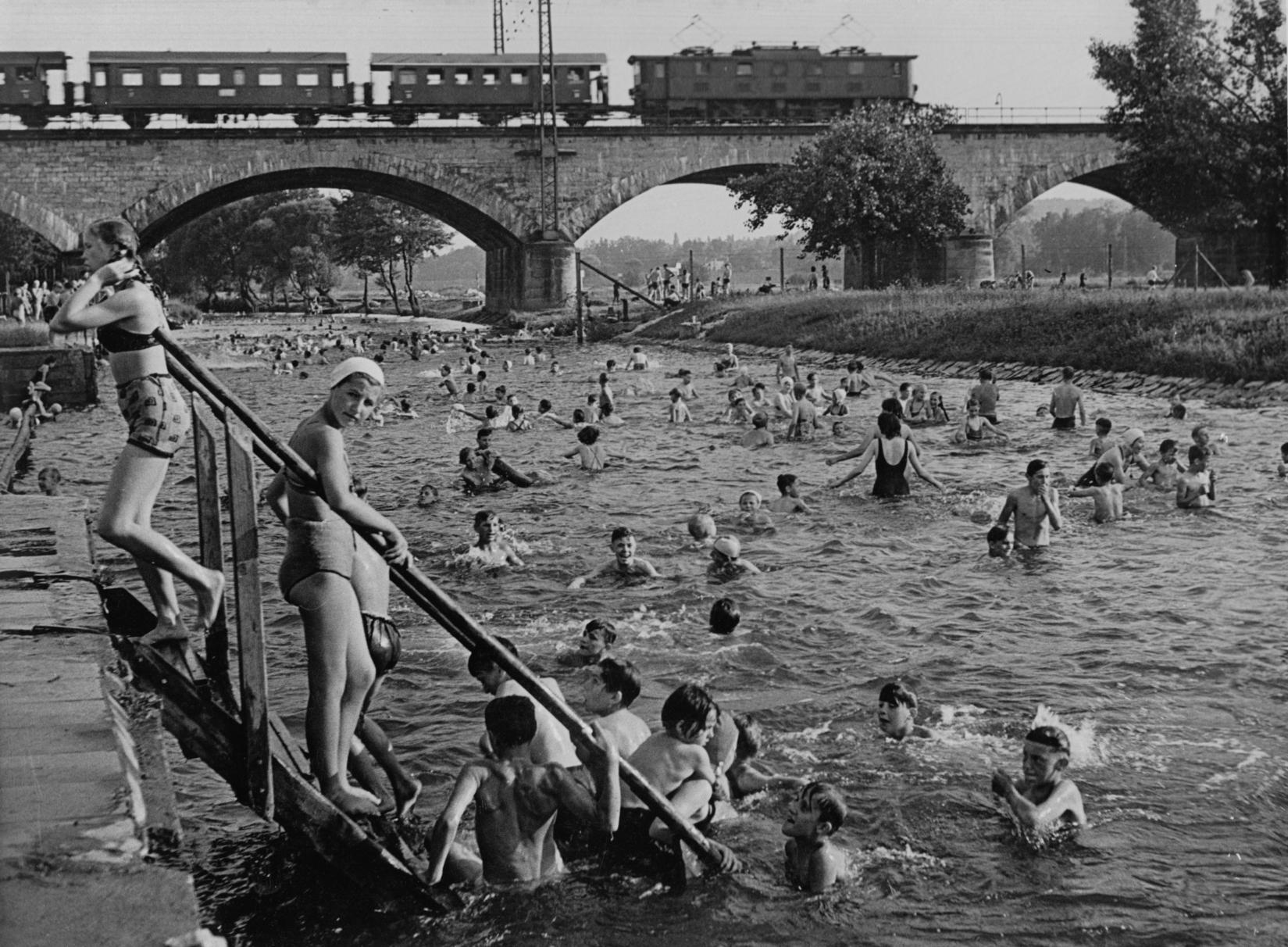 An heißen Tagen soll das Flussbad bis zu 12000 Badegäste angezogen haben. Ein Bild aus den 50ern mit Blick auf die Siebenbogenbrücke.