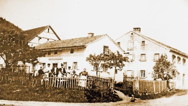 Dieses Foto zeigt die ursprüngliche Wirtschaft in Gstadt, die in dieser Form bis zum Jahr 1905 betrieben wurde. Inhaber war Georg Meyer. Das Gebäude ist heute noch in Familienbesitz und wird als Wohnhaus genutzt. Links neben der Wirtschaft ist die dazugehörige Scheune zu sehen, rechts das Anwesen Jungmeyer. Der Bergrücken links im Hintergrund ist der Patrichberg. Mehr zu der Geschichte des Anwesens lesen Sie hier.