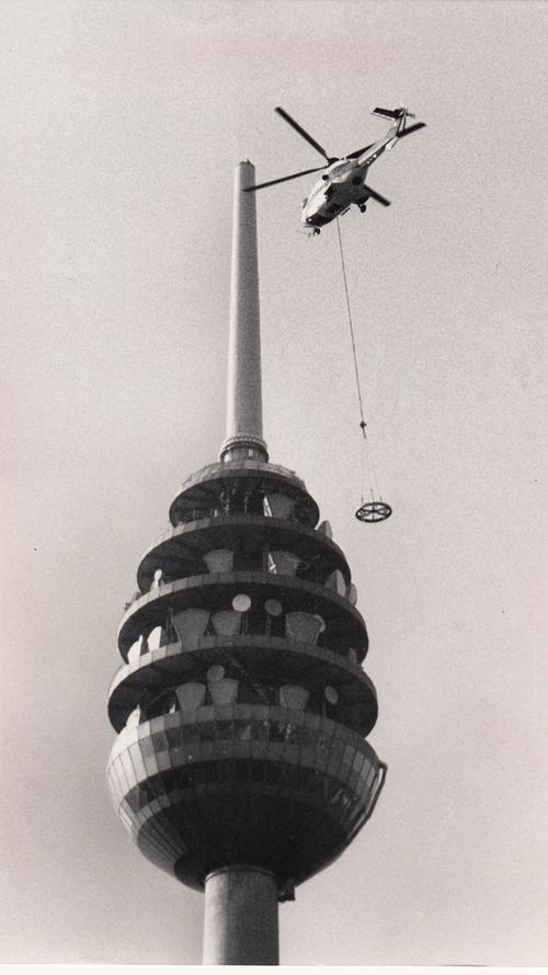 Das Ei wächst: 1991 gab es eine neue Mastspitze für zusätzliche Sendeanlagen. Bei diesem Flug schafft der Helikopter "Superpuma" den Verbindungsring auf den Turm, auf den später das 6,7 Meter lange Bauteil montiert wird