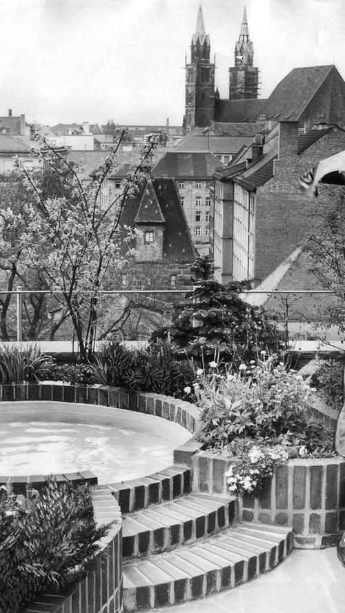 Schon in den 50ern trieb es die Leute aufs Dach. Familie W. genießt den Blick vom eigenen Dachgarten auf die St.-Lorenz-Kirche im Jahr 1957. Der Sohn gießt brav die Blumen neben dem Planschbecken.