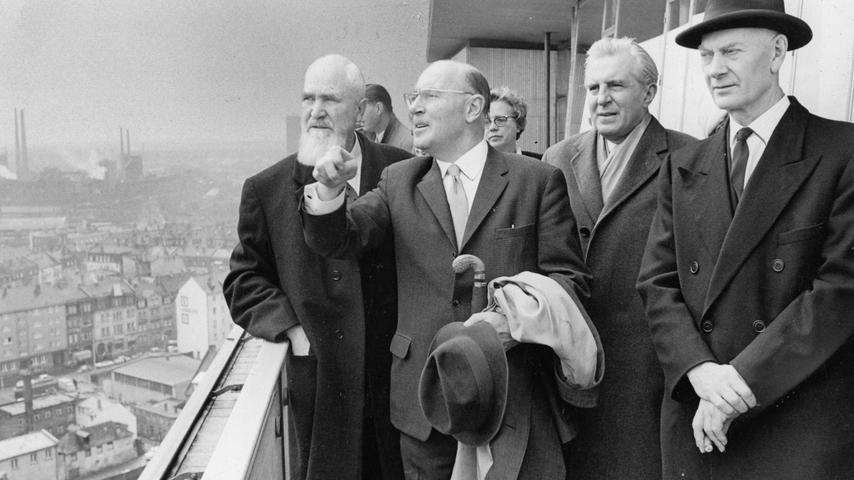 Auf der Dachterrasse des Hochhauses am Plärrer gibt Baureferent Schmeißner mit ausgestreckter Hand dem bayerischen Minister und dem norwegischen Ministerpräsidenten Hinweise über den Aufbau der Stadt. (Archivbild 1965)