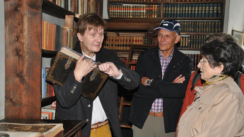 Gästeführer Reiner Benker zeigt die Bibliothek, das älteste Werk stammt von 1530. Der Name "alte Schwarte" kommt vom Schweinsleder, in das früher Bücher gebunden wurden.