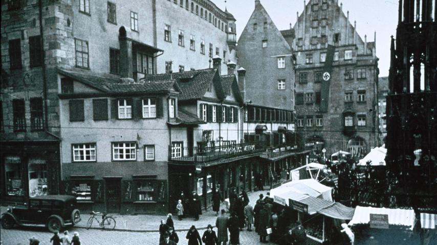 Nürnberg, im Jahr 1938: Die Rathausfassade zum Hauptmarkt hin war bis zum Zweiten Weltkrieg mit kleinen Häusern abgegrenzt. Eine ewig lange Hakenkreuzfahne baumelte über mehrere Stockwerke von ...