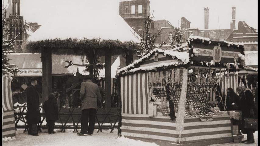 Auch dieses Bild stammt aus dem Jahr 1949. Es liegt Schnee, es ist kalt, die Stadt liegt in Trümmern (siehe Hintergrund). Trotzdem leben die Nürnberger ein Stück Normalität, besuchen den Christkindlesmarkt.