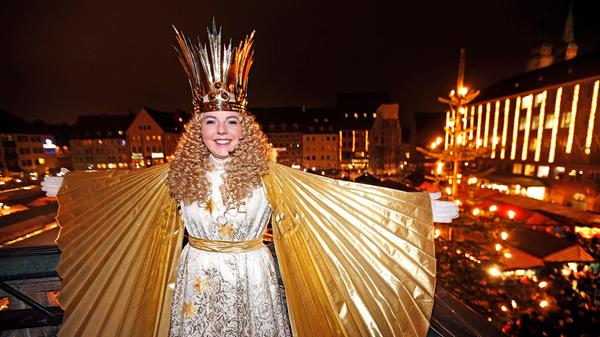 In ihrem ersten Jahr als Christkind präsentiert sich Barbara Otto stolz auf der Frauenkirche mit den Lichtern des Marktes im Hintergrund.