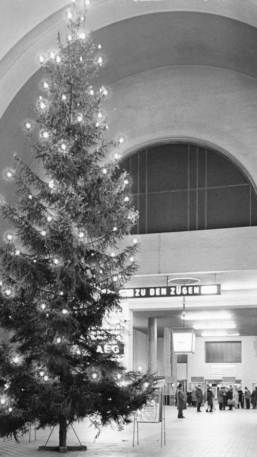 Gähnende Leere umgibt den Weihnachtsbaum in der Halle des Hauptbahnhofes. Nur an der Sperre warten einige Menschen auf ankommende Reisende.Hier geht es zum Artikel vom 27. Dezember 1965: Friedliche Festtage in Franken