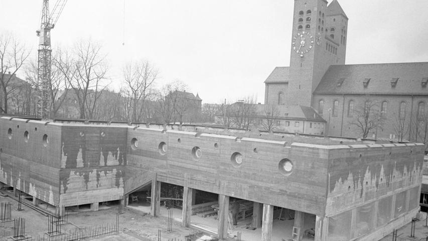 Durch die Drahtmaschen des Bauzauns können die Nürnberger "Wasserratten" schon das große Becken des neuen Hallenbades Süd betrachten, in dessen Fluten sie später fröhlich plantschen werden.
 Hier geht es zum Artikel vom 4. Januar 1966: Großes Schwimmbecken fast fertig