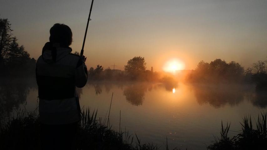 Ein Angler bei Sonnenaufgang an der Regnitz bei Vach.