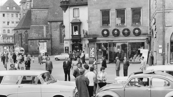 Am Hallplatz herrschte im Juni 1958 buntes Treiben. Passanten schlängelten sich unbeeindruckt an parkenden und fahrenden Autos vorbei.