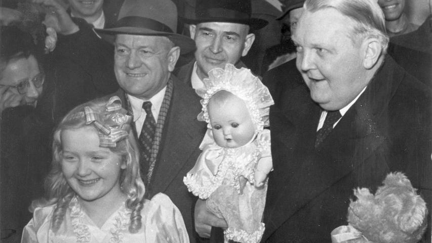 Die erste Spielwarenmesse 1950 lässt sich der gebürtige Fürther nicht entgehen. Im Arm hält er einen Spielzeugbär und eine Puppe. Besonders strahlt das Mädchen, ähnlich gekleidet wie die Puppe, auf der linken Seite. Ob da wohl der gleiche Ausstatter am Werk war?
