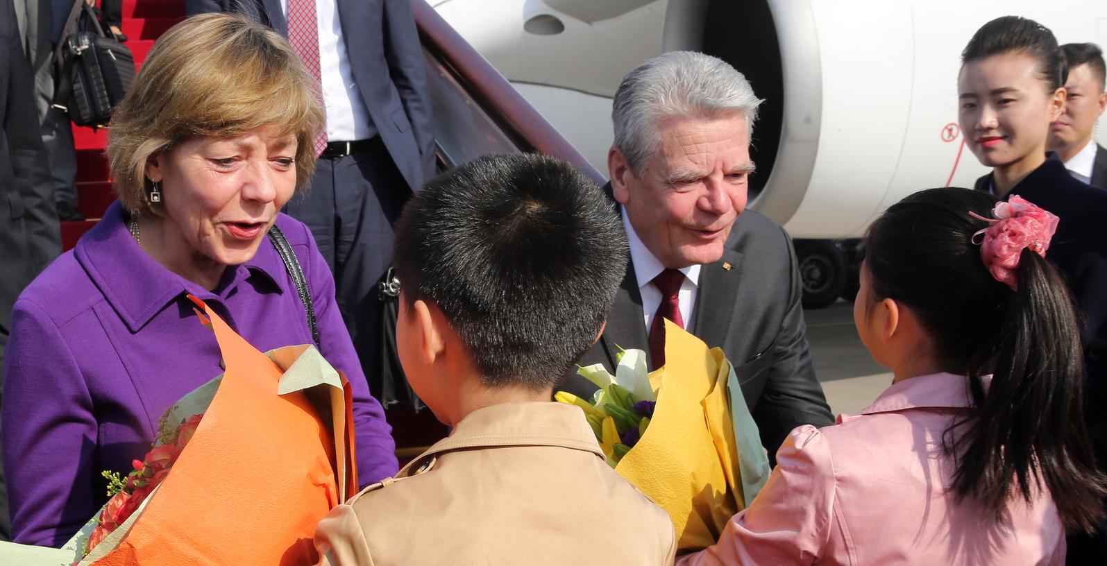 Joachim Gauck und seine Lebensgefährtin Daniela Schadt werden auf dem Flughafen von Peking von Kindern mit Blumen begrüßt. Menschenrechtler haben hohe Erwartungen an den China-Besuch des Bundespräsidenten.