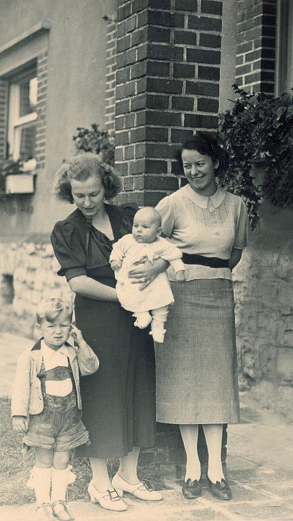 Adis Frau Käthe und Rudolfs Frau Friedel sind hier noch auf einem harmonischen Familienbild gemeinsam zu sehen. Die beiden verstehen sich aber nicht gut, was später das Zerwürfnis zwischen den beiden Brüdern begünstigt.