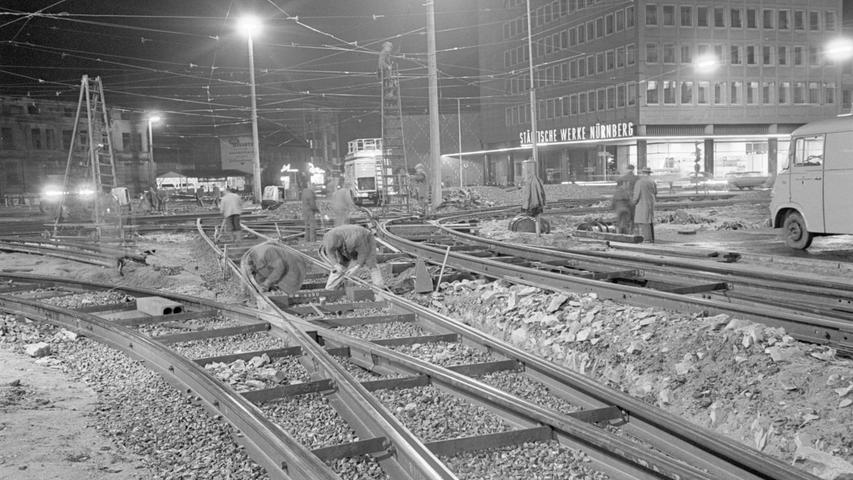 Ein eindrucksvolles Bild vom mitternächtlichen Gleisbau am Plärrer. Im Schienengewirr arbeiten die Männer an der Beseitigung der alten Stücke, die noch über dem neuen Netz liegen. Am dunklen Himmel spannt sich die Oberleitung, die ebenfalls geändert werden mußte. Hier geht es zum Artikel vom 14. April 1966: Nächtlicher Endspurt am Plärrer