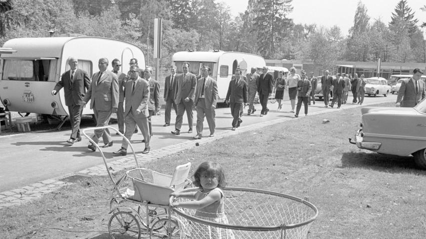 Sie schreiten aus, als ob sie alle selber "campen" wollten: Sportamtsleiter Georg Beil, Oberbürgermeister Dr. Urschlechter und Oberbaudirektor Görl (in der ersten Reihe von links). Einige Wohnwagenbesitzer hatten es sich schon gemütlich gemacht. Erstaunt schaut ein kleines Mädchen aus einem "Laufstall". <a href=http://www.nordbayern.de/region/nuernberg/15-mai-1966-rastplatz-im-wald-visitenkarte-1.5197793
 >Hier geht es zum Artikel vom 15. Mai 1966: Rastplatz im Wald – "Visitenkarte".