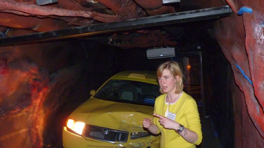 Anna Vodickova von der tschechischen Antidrogen-Initiative steht vor einem Autowrack — Sekunden zuvor war noch auf einer Leinwand die halsbrecherische Autofahrt von Jugendlichen unter Drogeneinfluss gezeigt worden.