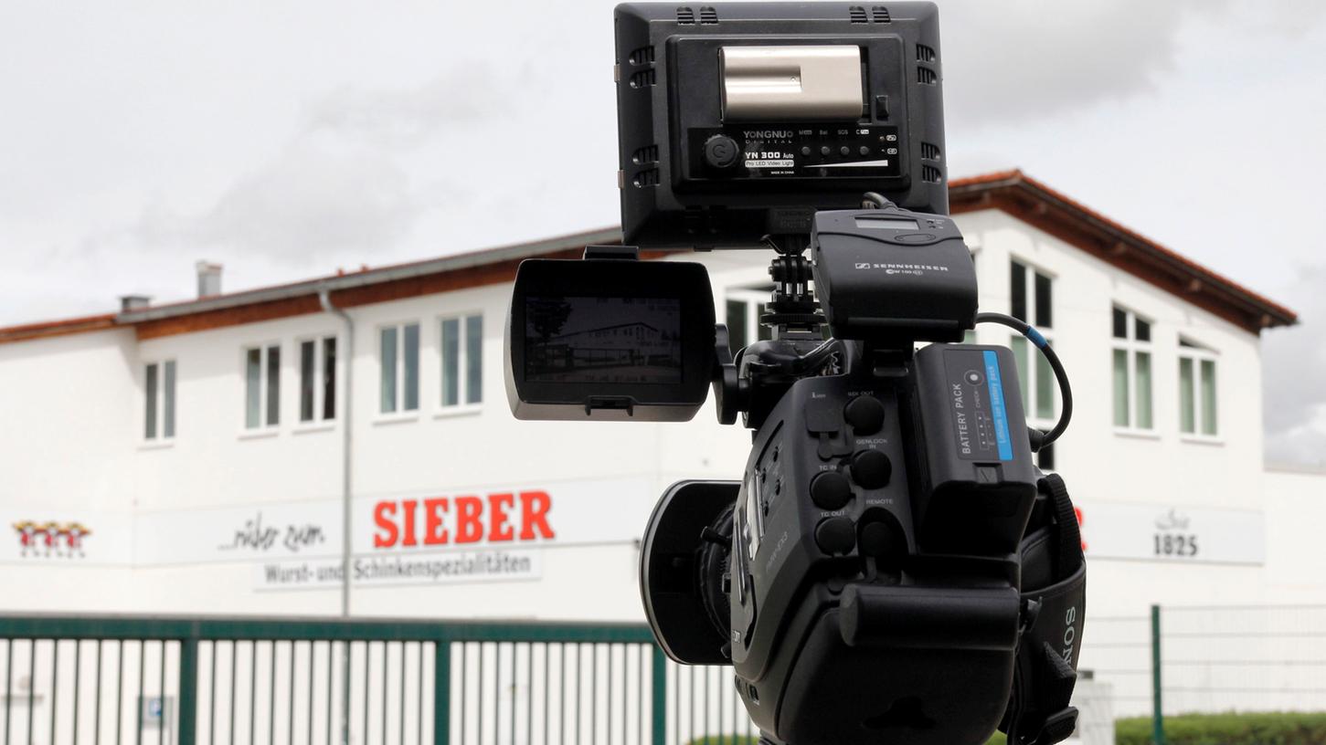 Eine Kamera steht in Geretsried vor dem Firmengelände der Fleischfirma Sieber. Sieber geht nach dem Fund von Bakterien in Wurstwaren gerichtlich gegen das behördlich angeordnete Produktionsverbot vor.