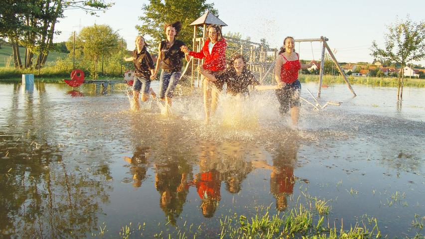 2007 steht ein Spielplatz in Raindorf unter Wasser. Schaukeln kann man hier vermutlich nicht, die fünf Mädchen haben dennoch ihren Spaß.