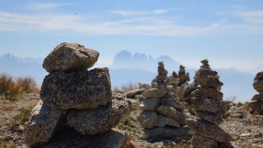Steinmännchen am Steinernen Mandl, dem Gipfelkreuz bei Jochtal. Im Hintergrund sieht man die schroffen Dolomiten.