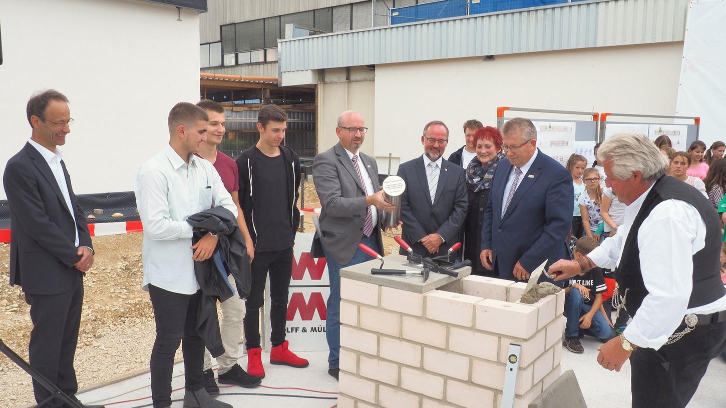 Die metallene Zeitkapsel soll später in den Boden der Aula eingelassen werden und an diesen Tag erinnern. Neben Schülern und Lehrern waren auch zahlreiche Ehrengäste zur Grundsteinlegung gekommen.