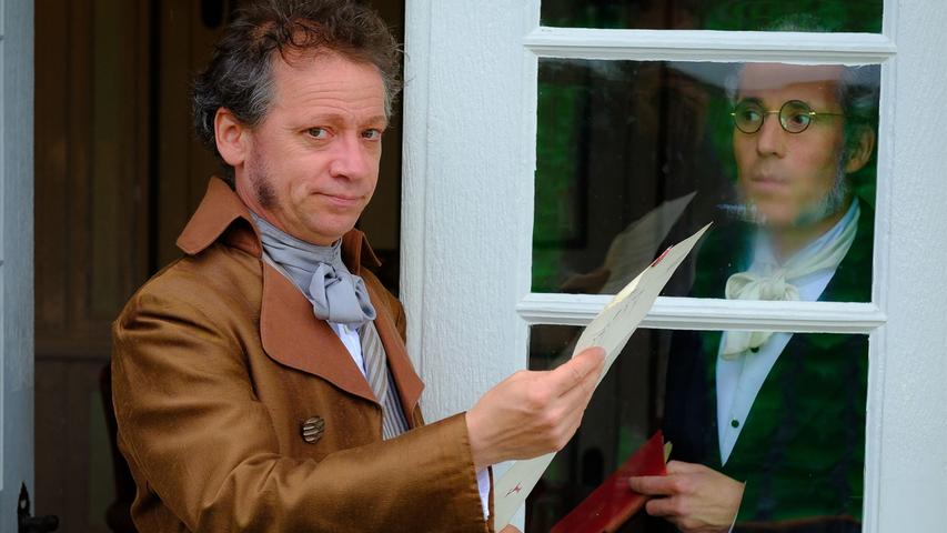 Der Graf von Seyl-Schaffenrath (Sven Tjaben) teilt dem Hauslehrer Holler (Matthias Weinhardt) mit, dass; hoher Besuch im Jagdschlößchen erwartet wird.