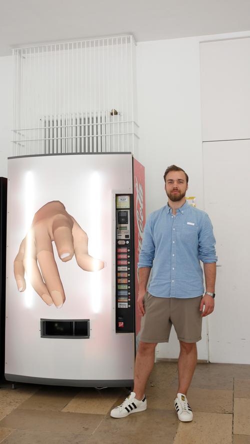 Die Hand weist auf den Betrachter. Jonas Tröger hat das Display vor den Getränkeautomaten montiert, und macht damit auch darauf aufmerksam, dass es in unserer Zeit stets um Input und Output geht. Für den Hakimi-Schüler, der den ersten Preis erhielt, ist der Automat der Prototyp dafür.