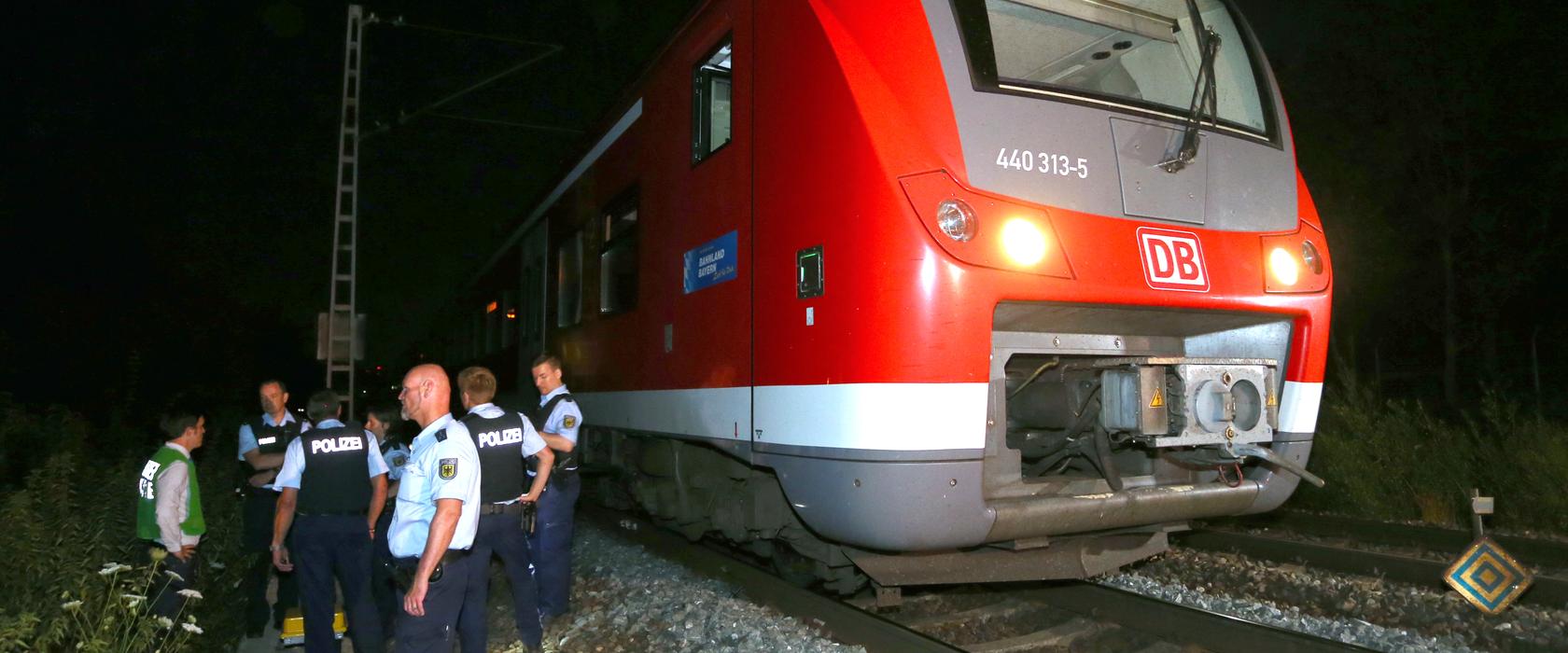 Polizisten stehen kurz nach der Tat in Würzburg neben einem Regionalzug. Ein Mann hatte in dem Zug Reisende angegriffen und mehrere Menschen lebensgefährlich verletzt.