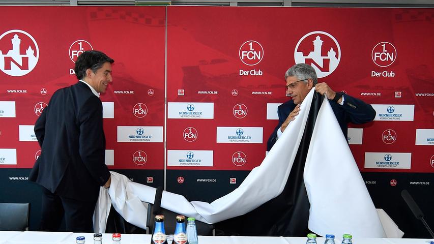 Bereits zu Beginn der Pressekonferenz ist es spannend: Michael Meeske und Dr. Armin Zitzmann enthüllen die neue Sponsorenwand des 1. FC Nürnberg. Mit dabei: das Logo der Nürnberger Versicherung.