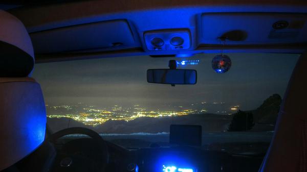 Aus der Sierra Nevada blickt man nachts durchs Wohnmobil-Cockpit auf das beleuchtete Granada herab.
