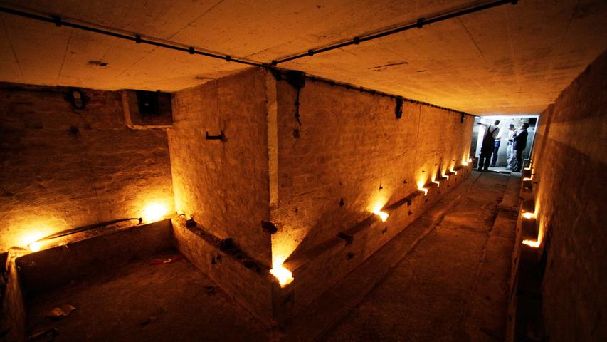 Kerzenlicht hellt den stockdunklen, langgezogenen Gang des Eibacher Splitterschutzgrabens auf. 