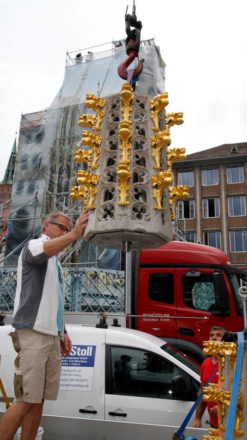 Ein besonderer Moment für viele Nürnberger: Der Schöne Brunnen auf dem Hauptmarkt erhielt nach monatelangen Restaurierungsarbeiten am Dienstag seine Spitze wieder.