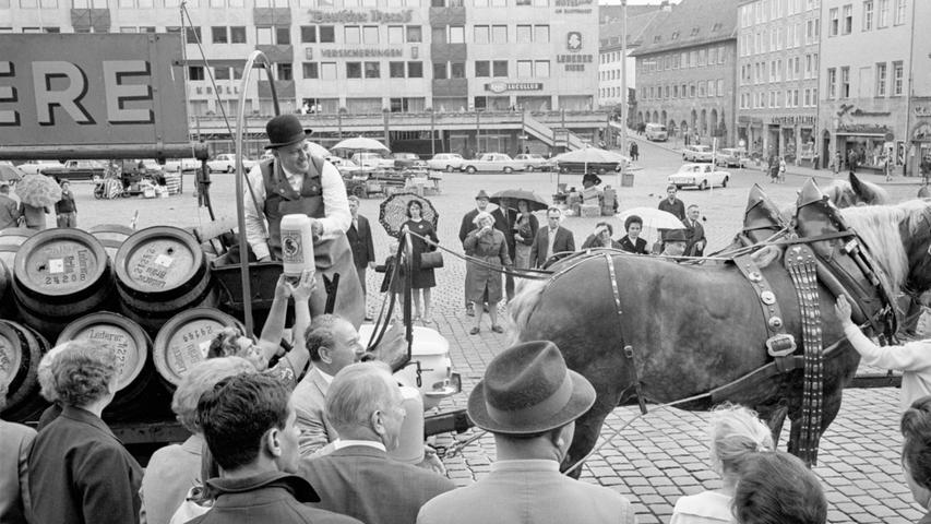 Der Kutscher gibt für die Marktfrauen und das übrige Publikum "einen aus". Sein Fuhrwerk erregt Aufsehen. <a href=http://www.nordbayern.de/region/nuernberg/9-august-1966-eine-ehrenrunde-im-galageschirr-1.5392334
 > Hier geht es zum Artikel vom 9. August 1966: Eine Ehrenrunde im Galageschirr.