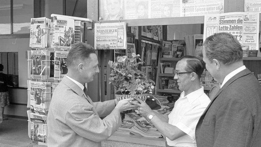 Er ist gestern in den neuen Zeitungskiosk am Plärrer-Pavillon eingezogen: Ferdinand Strohmann (Mitte) bekommt von Fritz Odoj Blumen überreicht.   Hier geht es zum Artikel vom 16. August 1966: Viel Glanz am Plärrer.