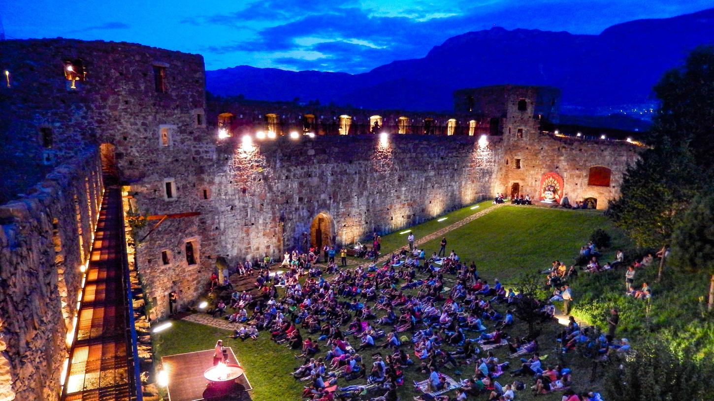 Abendstimmung auf Schloss Sigmundskron. Reinhold Messner sitzt neben der Feuerschale und plaudert über sein Leben. Die Besucher hören gebannt zu. Abendstimmung auf Schloss Sigmundskron. Reinhold Messner sitzt neben der Feuerschale und plaudert über sein Leben. Die Besucher hören gebannt zu.